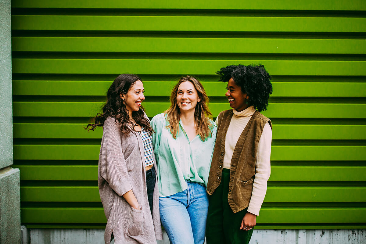 Three women standing in front of green house