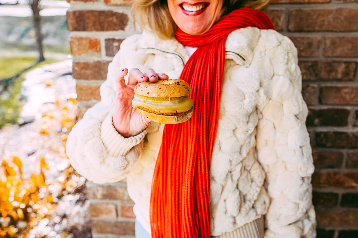 Woman smiling holding breakfast sandwich