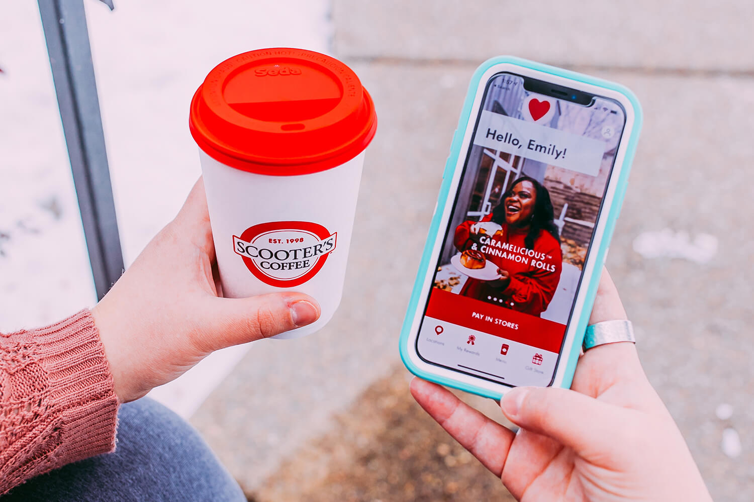 Person holding a Scooter's Coffee cup in their left hand and phone with Scooter's Coffee app in their right hand