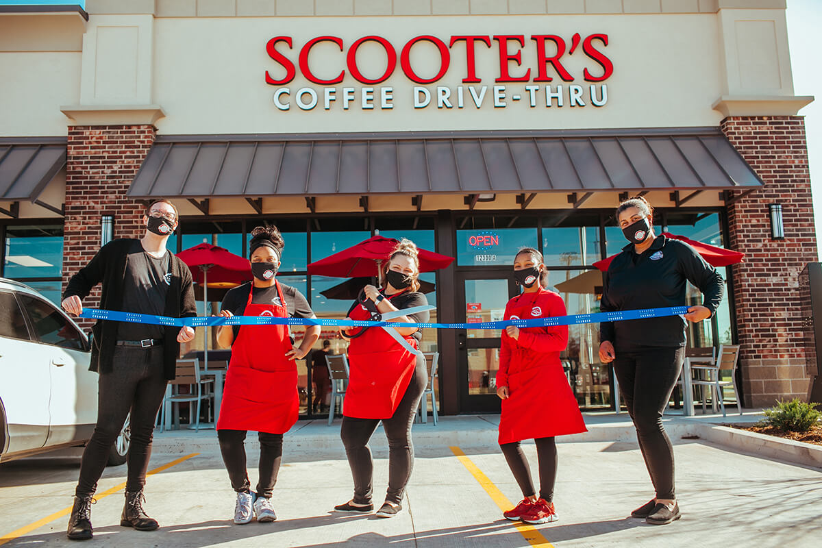 Five people cutting a ribbon standing in front of Scooter's Coffee