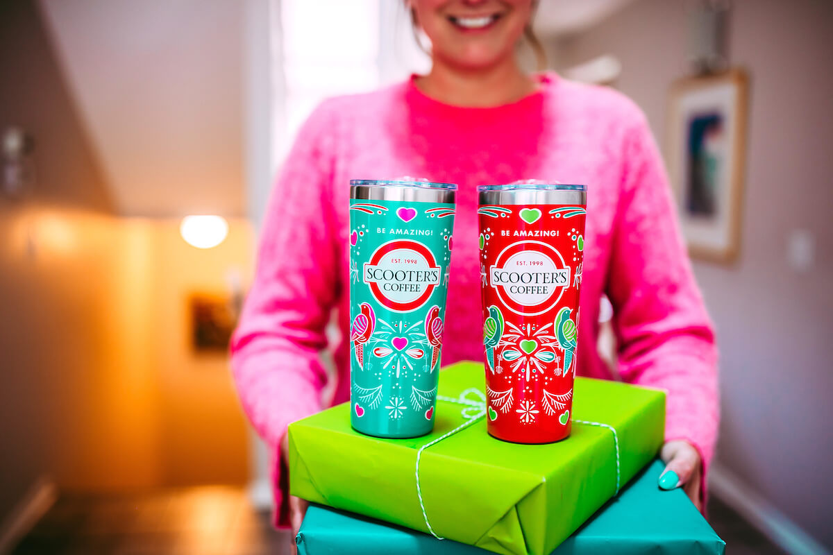 Woman holding two tumblers on top of presents