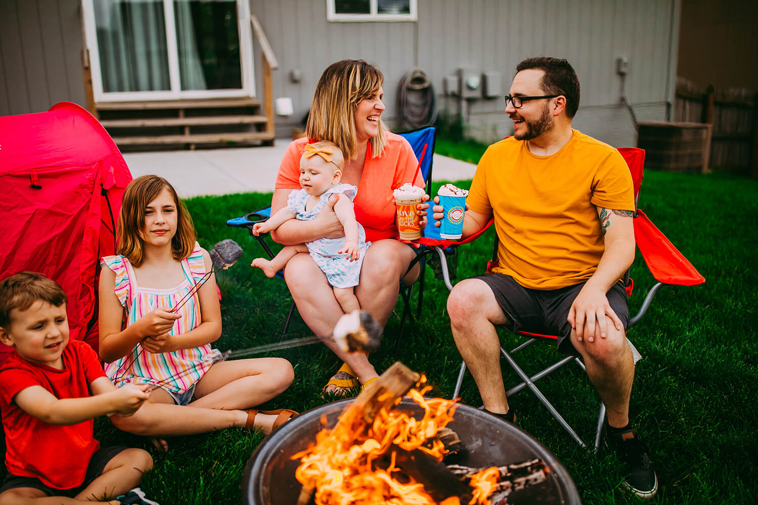 Parents and children in backyard around campfire