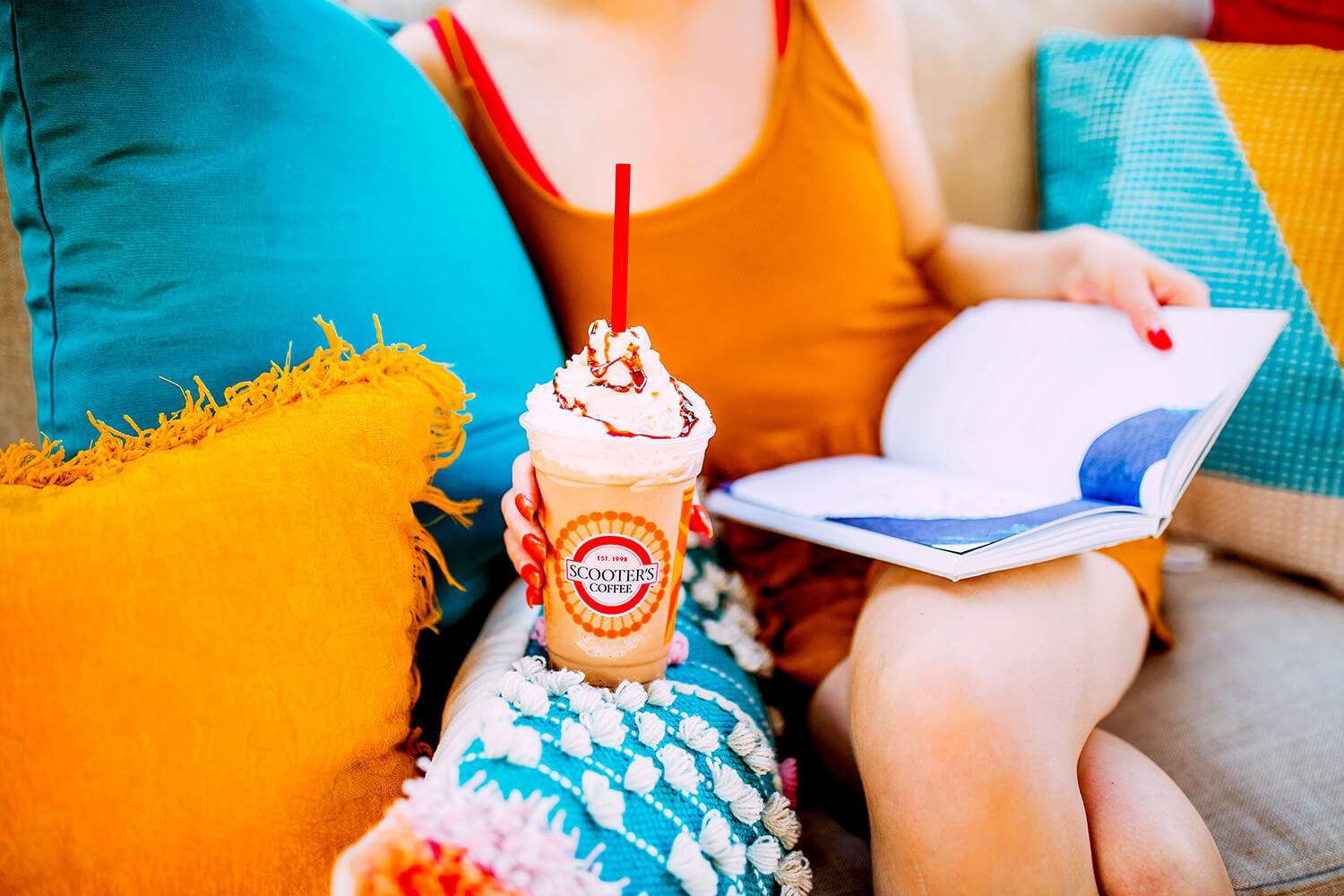 Woman on couch reading book holding coffee