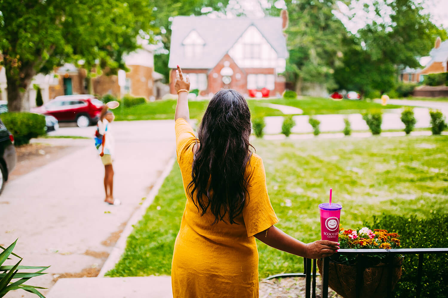 Woman holding pink cup waving bye to child