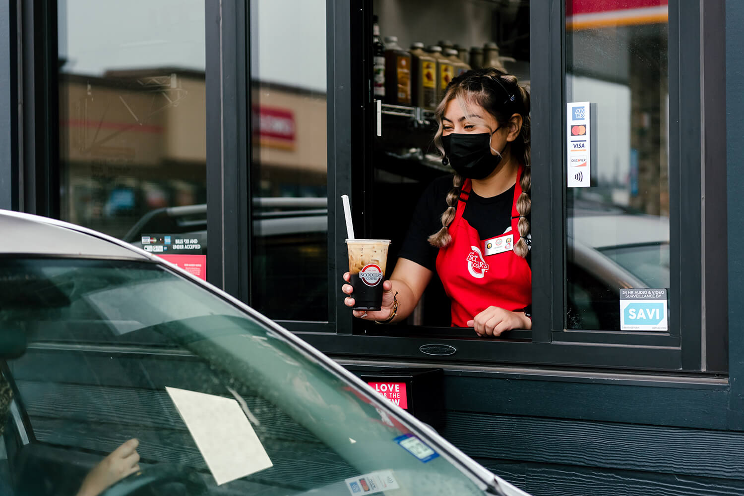 Barista handing coffee out of drive-thru window